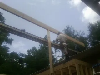 Carpenter setting a ridge beam over a new addition frame — Ice Dam Removal by Roofing Brothers in Whitmore Lake
