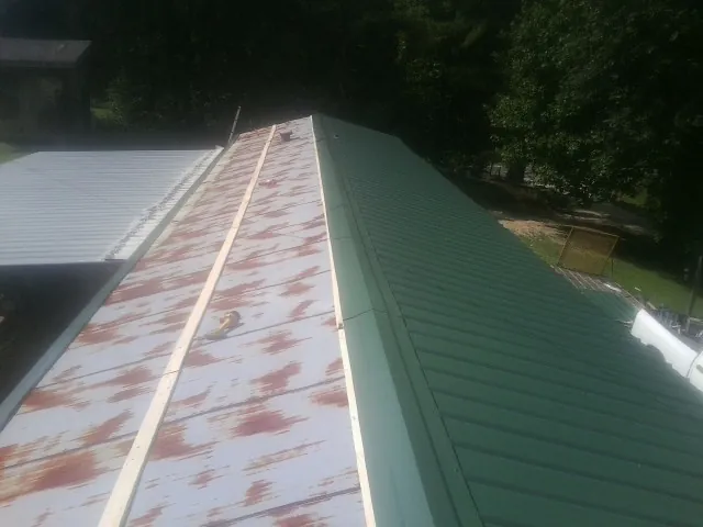Old rusted panels beside newly installed green metal roofing — Wind Damage Roof Repair by Roofing Brothers in Whitmore Lake
