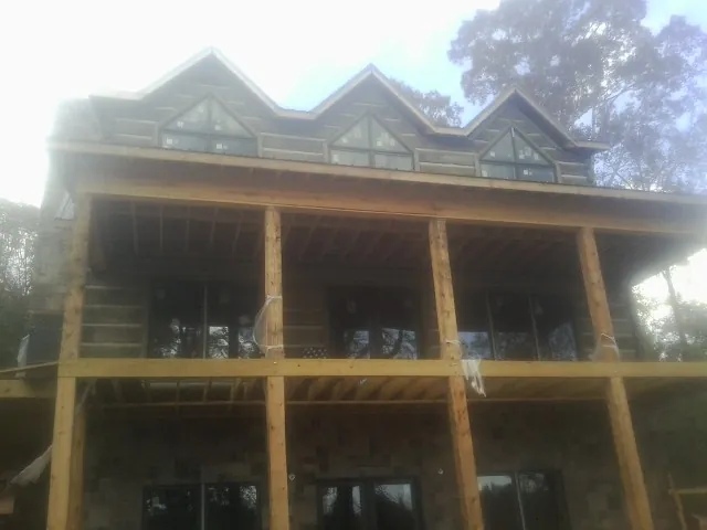 Dormers and porch framing on a large log home under construction — Roof Coating work by our crew in Whitmore Lake