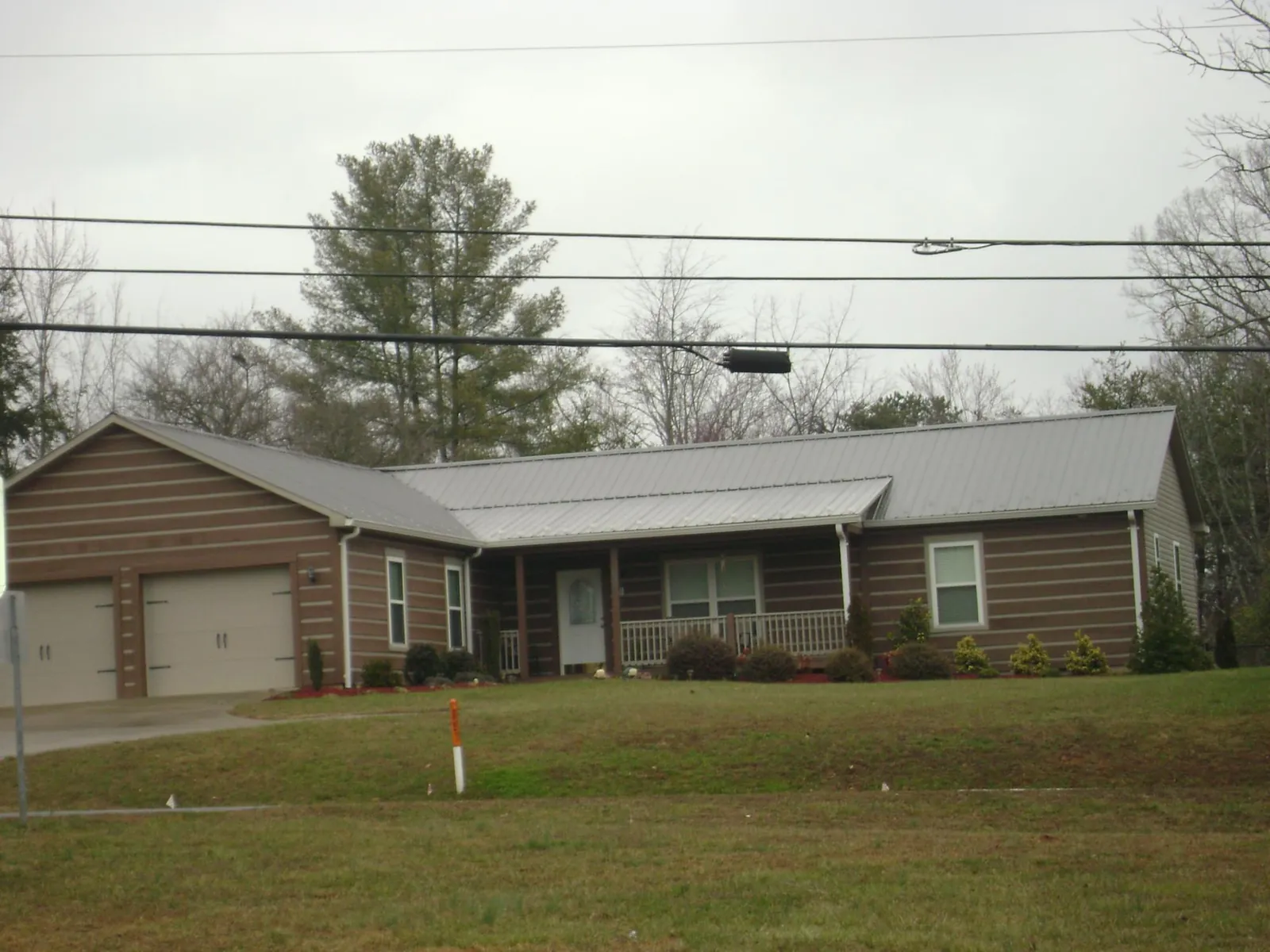 Gray metal roof on a log sided ranch home with a front porch in Whitmore Lake